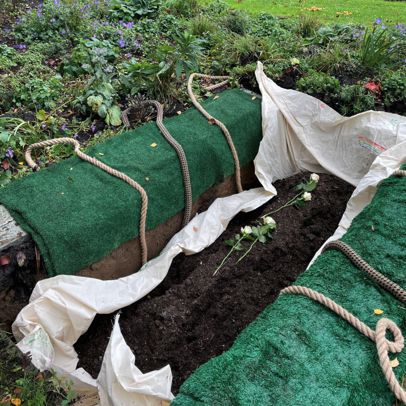 Grab mit neuer Erde, die mit Rosen bedeckt ist