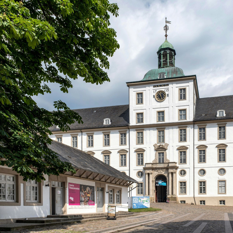 Ein hohes weißes Gebaeude in Schleswig mit goldener Uhr