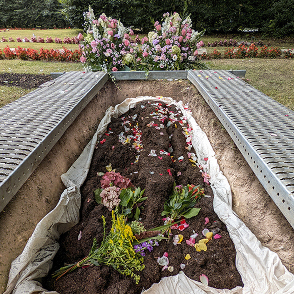 Einbringung der Erde mit Blumen bei einer Reerdigung